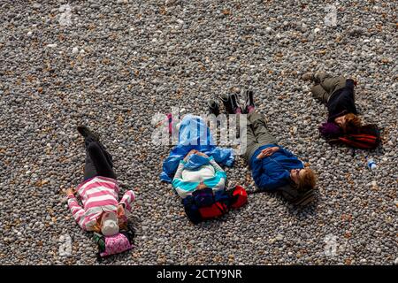 Isle of Wight, UK 04/25/2010: Un gruppo di giovani adulti in abbigliamento da trekking casual si trovano sulla spiaggia di ciottoli e godersi il sole mentre si riposa e t Foto Stock