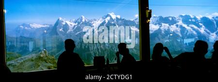 I turisti al ristorante Schilthorn 007 con Monte Eiger Mt Monch Mt Jungfrau sullo sfondo, Oberland Bernese, Svizzera Foto Stock