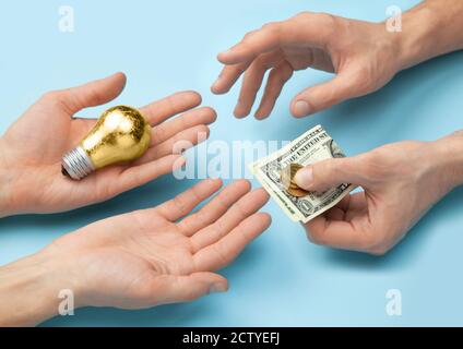 Vendere idee per soldi. Lampadina come un simbolo di idea. Le mani di un uomo danno un'idea e prendono i soldi. Foto Stock