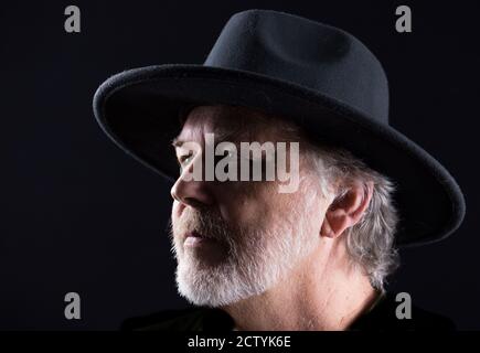 Ritratto in primo piano di un uomo di mezza età in un cappello occidentale largo-brimmed su uno sfondo scuro Foto Stock