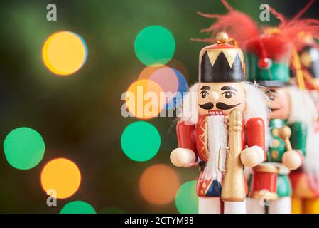 Tradizionali nutcracker di Natale colorati con uno sfondo verde con luci colorate fuori fuoco, spazio di copia Foto Stock