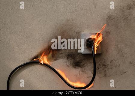 Presa elettrica a filo sul fuoco sulla parete di cemento esposta a fondo in cemento con spazio per copia Foto Stock