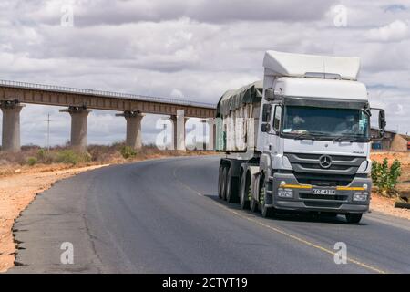 Un grande camion che guida lungo l'autostrada Mombasa che trasporta merci con la ferrovia SGR in background, Kenya Foto Stock