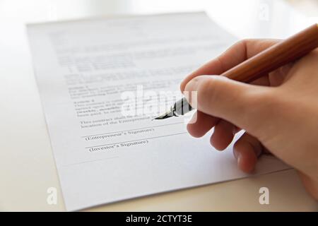 Firma del contratto con una penna stilografica in legno. Bella scrittura a mano. Foto Stock