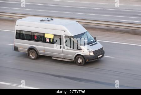 Piccolo bus bianco va in autostrada in sera Foto Stock