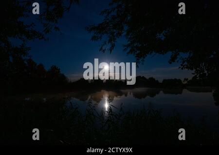 sopra un lago le stelle e la luna possono essere visto nel cielo notturno Foto Stock