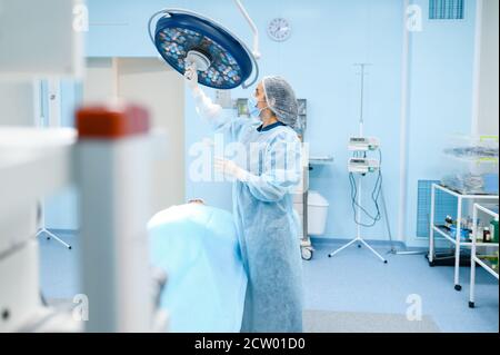 La chirurgo femminile prepara la lampada in sala operatoria Foto Stock