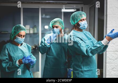 Team di chirurgo medico al lavoro dopo l'intervento in ospedale Durante l'epidemia di pandemia di coronavirus - Focus sul volto del medico di destra Foto Stock