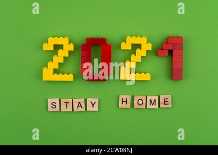 Le parole rimangono a casa 2021 è fiancheggiata da lettere di legno su uno sfondo verde. Figure dalla vista dall'alto del costruttore. Cartolina per il testo Foto Stock