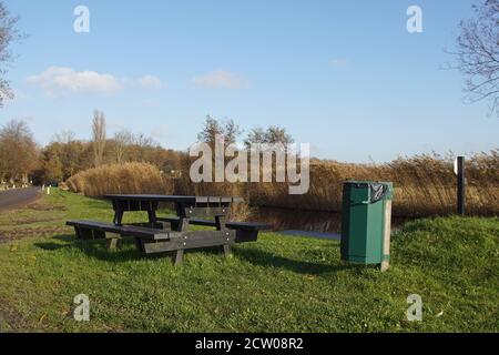 Panca di legno e tavolo in erba lungo una strada e un fosso con canna in autunno vicino al villaggio olandese di Bergen. Novembre, Paesi Bassi. Foto Stock