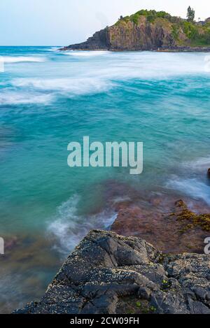 Leggermente sfocate, prima dell'alba, le onde bianche si avvolgono verso una costa rocciosa del nuovo Galles del Sud, spiaggia della costa settentrionale in Australia Foto Stock