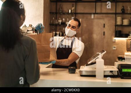 Cliente che paga e riceve l'ordine al bar contatore durante la quarantena Foto Stock