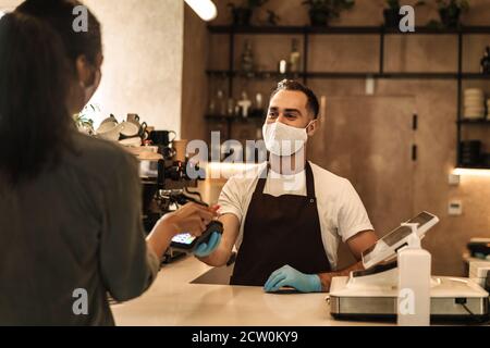 Cliente che paga e riceve l'ordine al bar contatore durante la quarantena Foto Stock