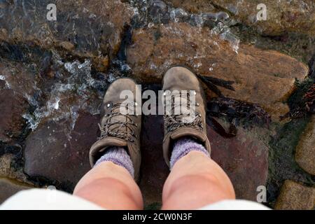 Coast to Coast Walk, Regno Unito - stivali da immersione nel mare del Nord alla fine della passeggiata, Robin Hoods Bay, North Yorkshire, Inghilterra, Regno Unito Foto Stock