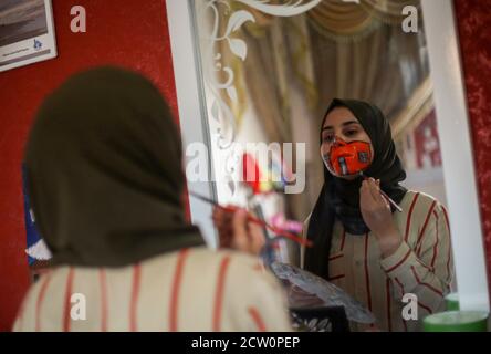 Ragazza palestinese, Ranin al Zeriei (19) guarda attraverso lo specchio mentre dipinge una maschera sul suo volto. Nella striscia di Gaza meridionale della città di Deir al Balah, 25 settembre 2020. Per sensibilizzare l'opinione di indossare una maschera protettiva in mezzo allo scoppio del Coronavirus (Covid-19) a Gaza. (Foto di Yousef Masoud/INA Photo Agency) Foto Stock