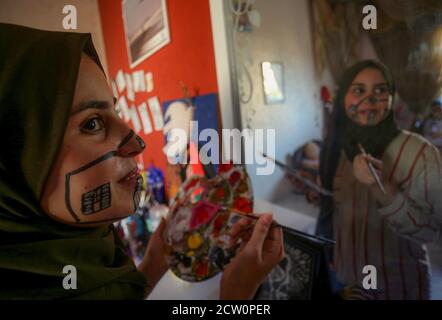 Ragazza palestinese, Ranin al Zeriei (19) guarda attraverso lo specchio mentre dipinge una maschera sul suo volto. Nella striscia di Gaza meridionale della città di Deir al Balah, 25 settembre 2020. Per sensibilizzare l'opinione di indossare una maschera protettiva in mezzo allo scoppio del Coronavirus (Covid-19) a Gaza. (Foto di Yousef Masoud/INA Photo Agency) Foto Stock