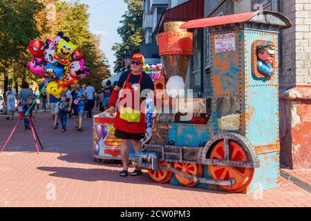 Kremenchug, Ucraina - 22 settembre 2018: Uomo che vende caramelle di cotone durante il festival Sweet Kremenchug. Processo di produzione di caramelle di cotone Foto Stock