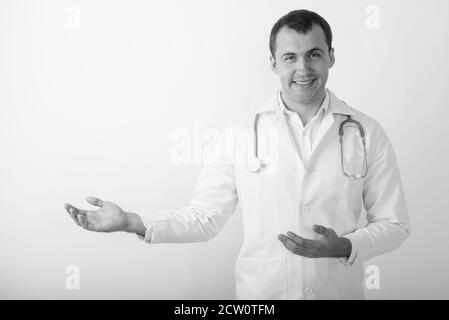 Studio shot di giovani felici muscolare medico uomo sorridente mentre mostrando qualcosa contro uno sfondo bianco Foto Stock
