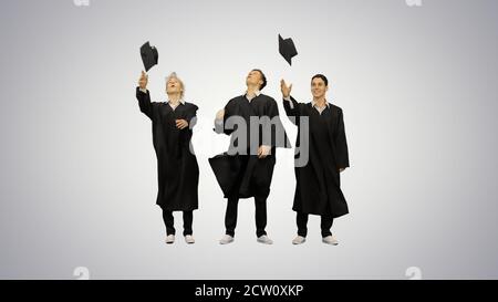 Tre diplomati maschi felici che gettano mortarboard in aria e. Foto Stock