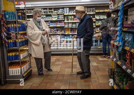 Coppie anziane che effettuano il loro shopping in un supermercato di Londra durante la pandemia di Coronavirus che indossa maschere obbligatorie per il viso, Inghilterra, Regno Unito Foto Stock