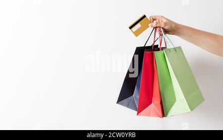 Donna mano che tiene il gruppo di sacchetti colorati di carta e carta di credito su sfondo bianco. Concetto di banner per lo shopping. Foto Stock