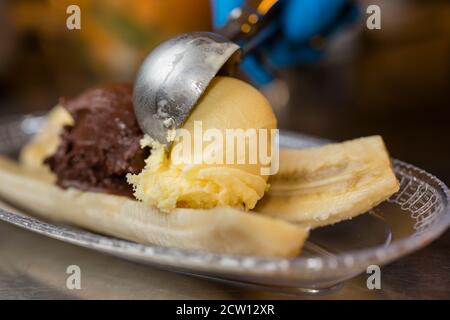 Preparazione di crosta artigianale di Banana italiana con gelato, panna montata, ciliegie e cuocie di lingua di gatto. Foto Stock