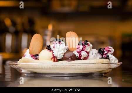 Preparazione di crosta artigianale di Banana italiana con gelato, panna montata, ciliegie e cuocie di lingua di gatto. Foto Stock