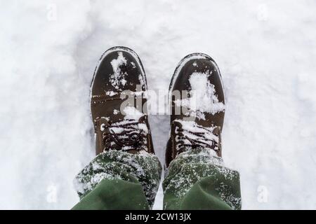 Piedi maschi in stivali che camminano lungo nella neve d'inverno Foto Stock