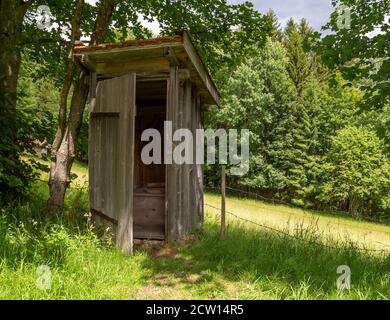 storica latrina di buca in legno in un ambiente verde soleggiato Foto Stock