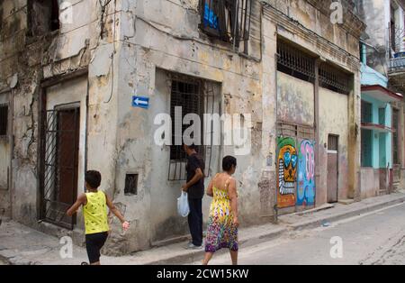 L'Avana, Cuba, una strada laterale che mostra tre persone, un uomo, una donna e un bambino, tutte apparentemente scollegate Foto Stock