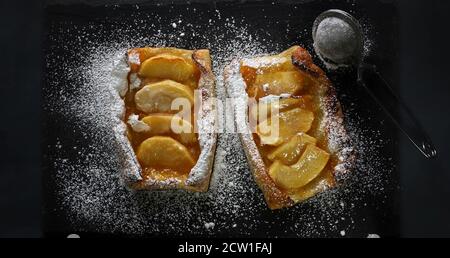 Crostata di mele con zucchero a velo su fondo scuro. Foto Stock