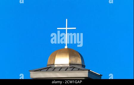 Croce bianca aganista un cielo blu in cima all'oro Cupola della chiesa cattolica Foto Stock