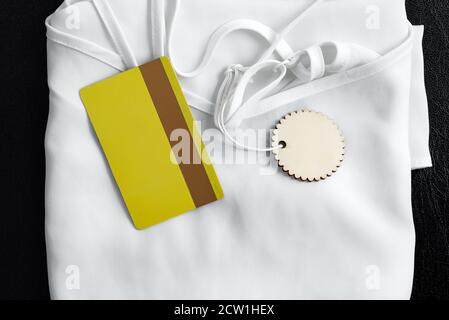 Nuovi abiti bianchi donna con etichetta e mock-up sconto o carta di credito giallo su sfondo nero. Vista dall'alto. Vendita del Black Friday. Foto Stock