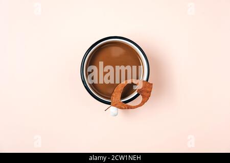 Creativo autunno piatto posa in alto vista dall'alto caffè latte latte tazza latte e foglia secca con cuore intagliato su sfondo beige copia spazio stile minimal. Mare di caduta Foto Stock
