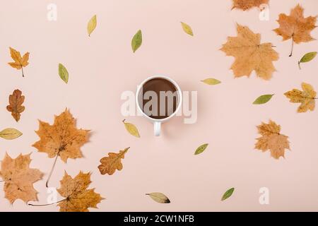 Composizione autunnale. Tazza di caffè, asciugate varie foglie su sfondo rosa pastello. Autunno, autunno concetto. Disposizione piatta, vista dall'alto Foto Stock