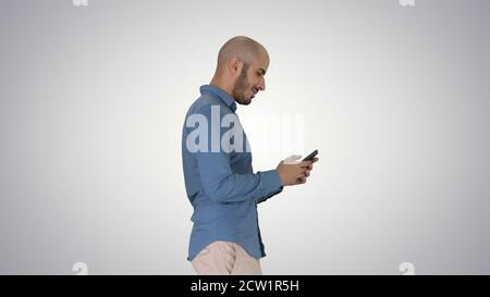 Giovane uomo che cammina e usa un telefono su sfondo sfumato. Foto Stock