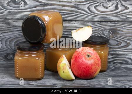 Marmellata di mele in vasi. Nelle vicinanze si trovano le fette di mela. Su tavole spazzolate, verniciate in bianco e nero. Foto Stock