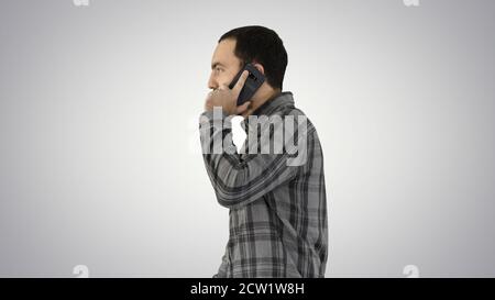 Cool giovane uomo con la barba a camminare e parlare con il telefono cellulare Foto Stock