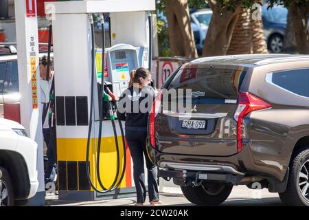 Donna che mette il carburante nella sua auto a una conchiglia di Sydney Distributore di benzina, Sydney, Australia Foto Stock