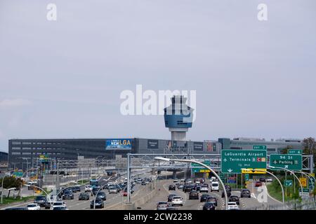 Auto sull'autostrada che porta all'aeroporto LaGuardia. Torre di controllo del traffico aereo vista sopra i terminali Foto Stock