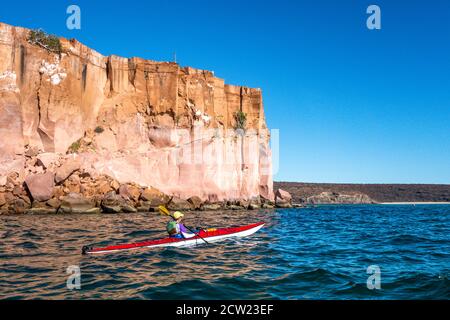 Un kayak passa accanto alle scogliere nel mare di Cortez mentre circumnaviga Isla Espirituu Santo al largo della penisola di Baja California, Messico. Foto Stock