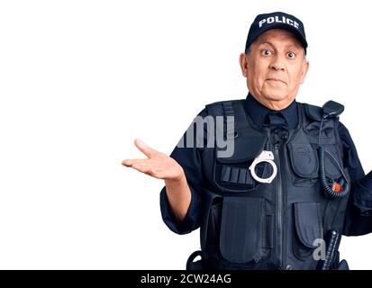 Alto bell'uomo che indossa la polizia uniforme indiziato e confuso espressione con armi e mani sollevato. Concetto di dubbio. Foto Stock