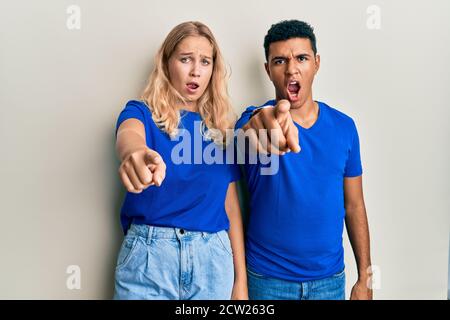 Giovane coppia interracial che indossa abiti casual puntando dispiaciuto e frustrato alla macchina fotografica, arrabbiato e furioso con voi Foto Stock