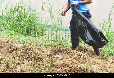 Volontari dell'uomo che aiutano a mantenere la natura pulita e a raccogliere La spazzatura da parco / riciclaggio e tecniche di riduzione dei rifiuti che aiutano l'ambiente Foto Stock