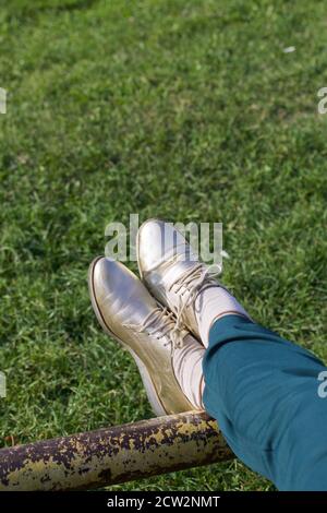 Ragazza in tuta verde e scarpe dorate. Su uno Sportsground. Primo piano delle gambe. Foto Stock