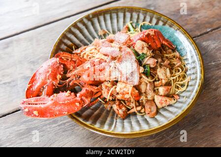 Aragosta alla griglia salsiccia prosciutto verdure e formaggio spaghetti frutti di mare su Tavola di legno / frutti di mare mollusco piatto con aragosta cena cibo cotto Foto Stock