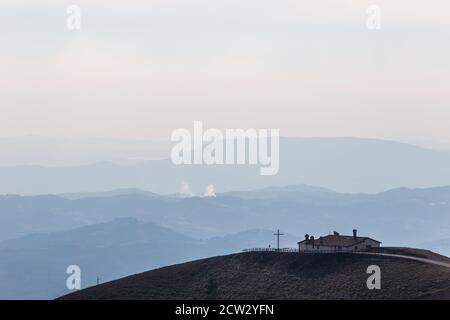 Veduta dell'eremo Serrasanta Umbria, Italia in cima ad una montagna, con diversi altri strati di montagna sullo sfondo Foto Stock