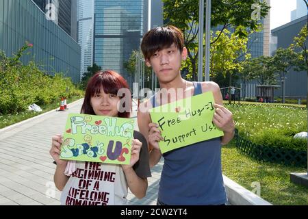 Hong Kong, Hong Kong, Cina. 5 Ott 2014. La rivoluzione di Umbrella del 2014; Gwen Chan, 14, e Frank Wong, 20, offrono hugs gratuiti a Tamar Park al di fuori degli uffici governativi e Chief Executive. Credit: Jayne Russell/ZUMA Wire/Alamy Live News Foto Stock