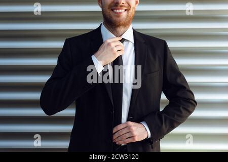 Uomo d'affari raddrizza la sua fascetta. Uomo d'affari fresatura in tuta nera. Foto Stock