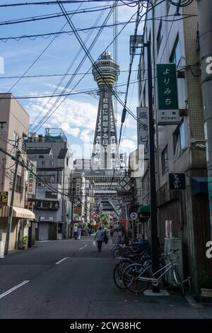 Vista della Torre Tsutenkaku a Shinsekai, Osaka, Giappone, che mostra le strade intorno alla torre, in un pomeriggio di sole. Foto Stock